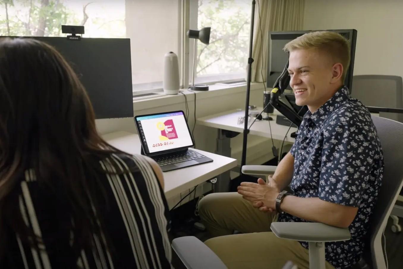 Two people talking in front of a computor