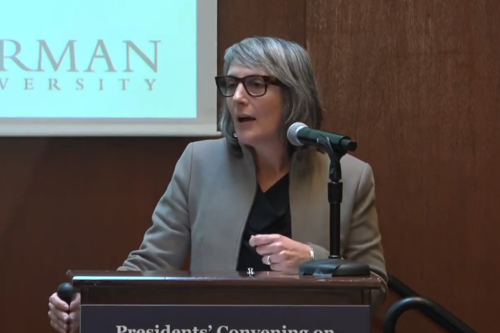 Woman in grey jacket on stage