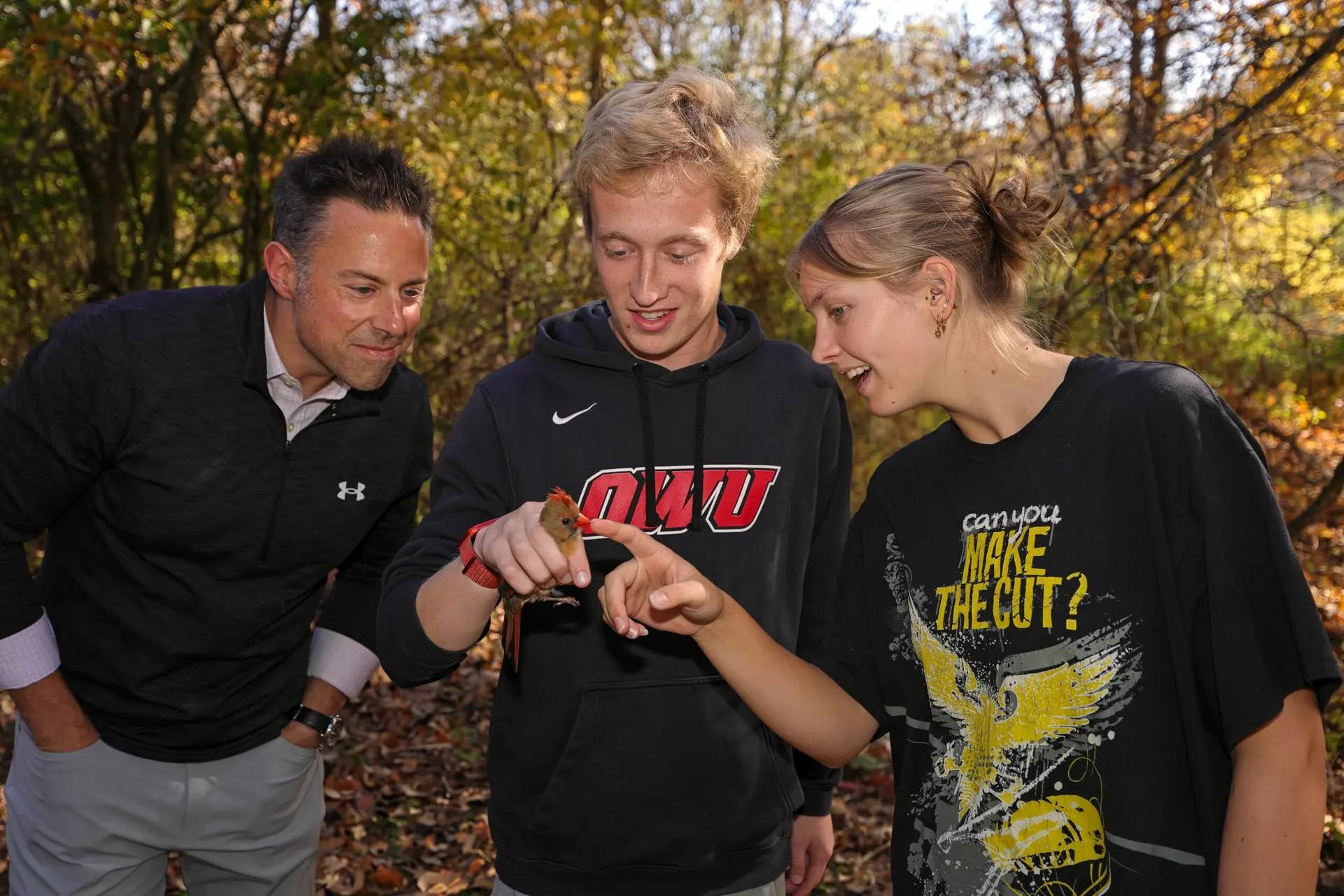 Three people holding a small bird