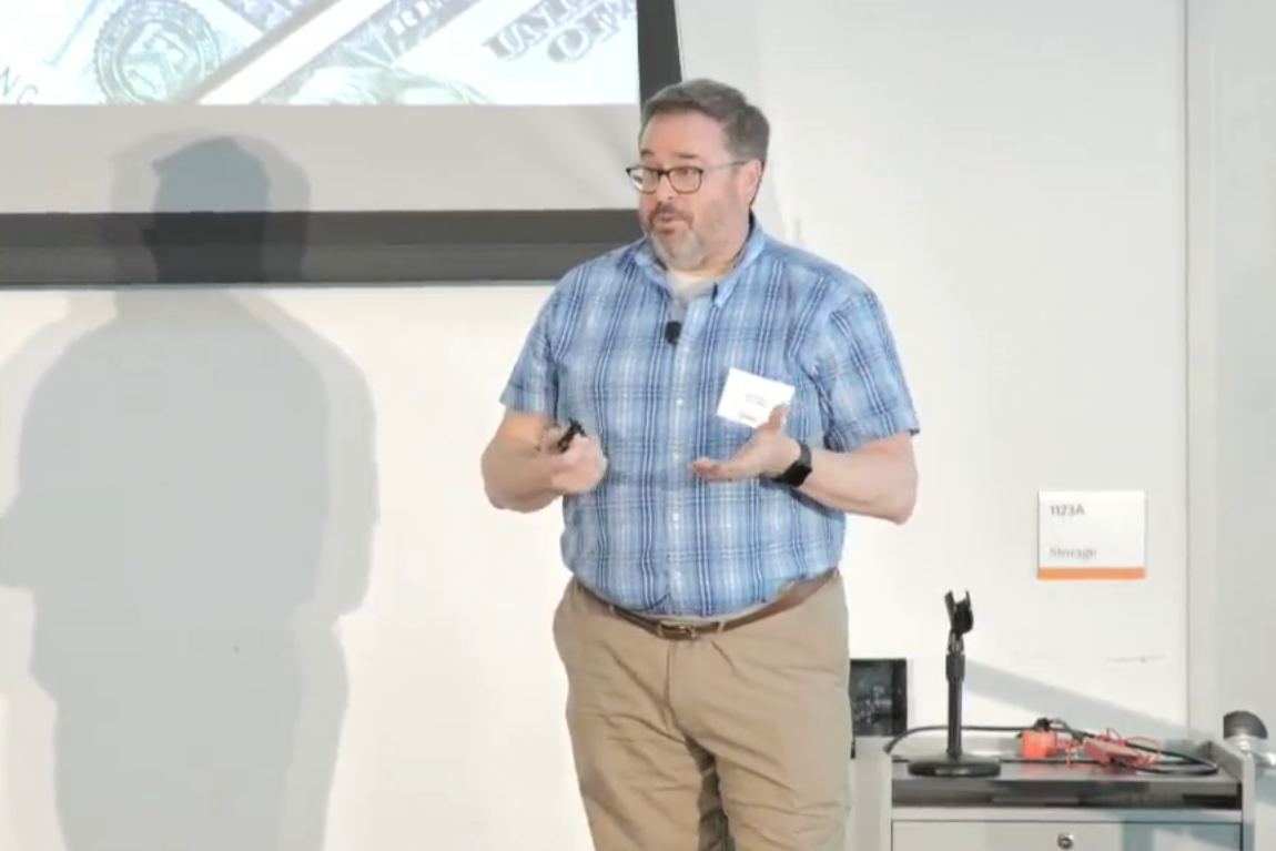 Man talking in front of a screen