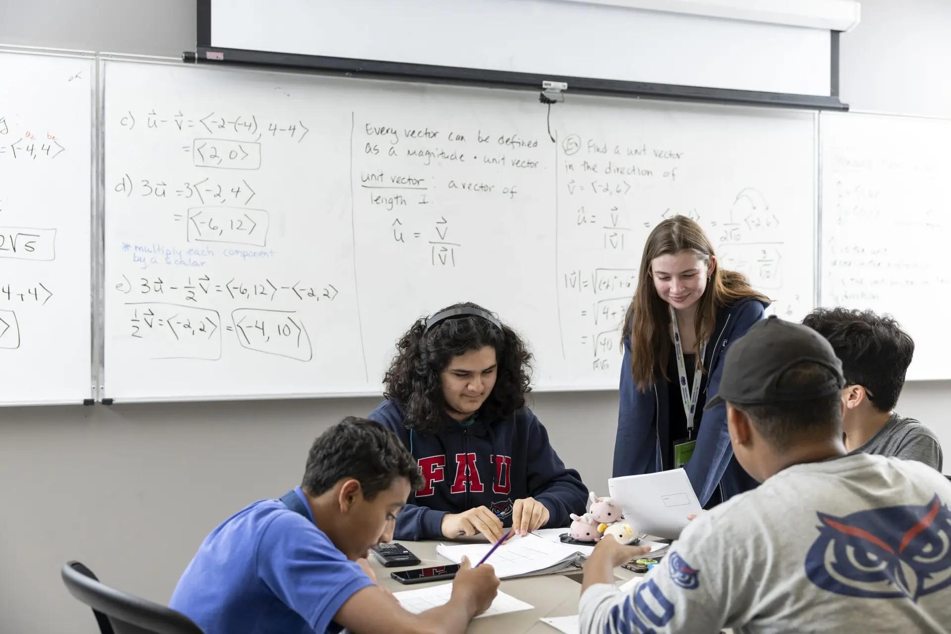 People gathering around a table in a classroom setting